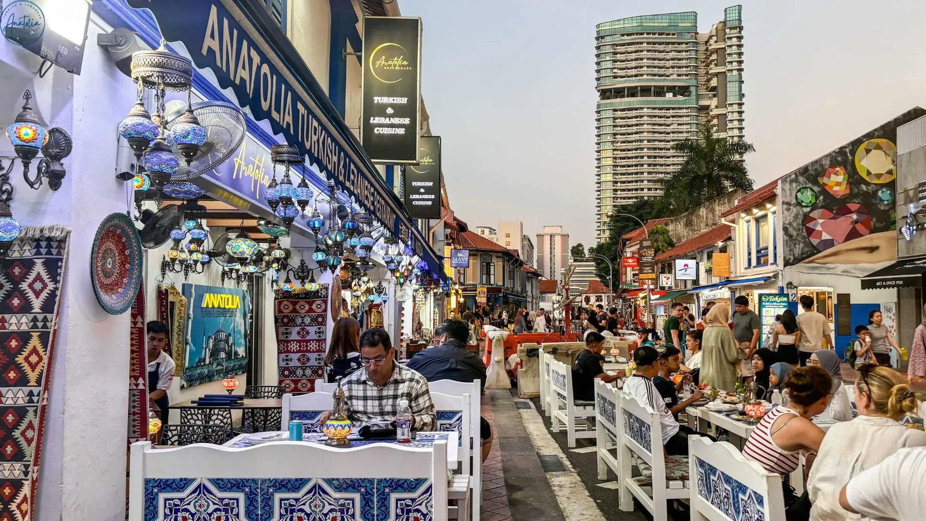 Families breaking fast on Arab Street Singapore with Masjid Sultan at sunset during Ramadan
