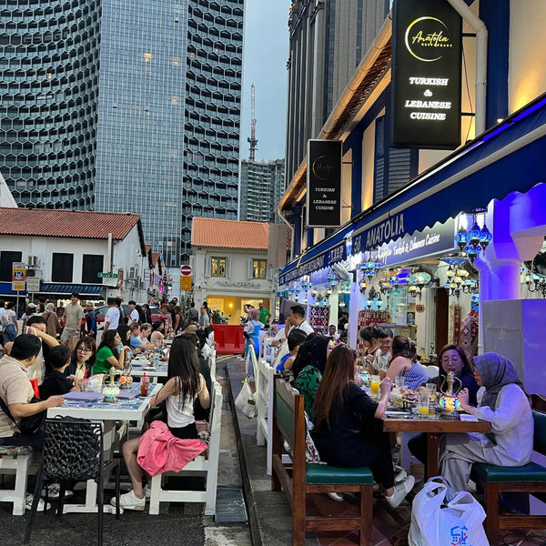 Outdoor dining scene at Anatolia Restaurant in Singapore featuring Turkish and Lebanese cuisine along Arab Street with guests enjoying dinner under city lights.